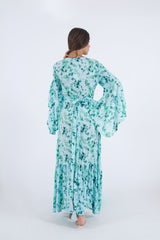 Image of model back side wearing our long wrap dress in floral pattern with bell sleeves.