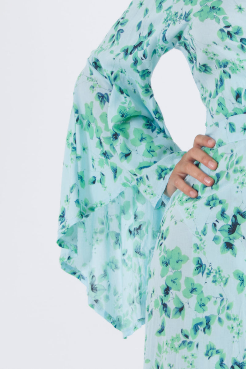 Detail of trumpet sleeve from our long wrap dress in green floral pattern.