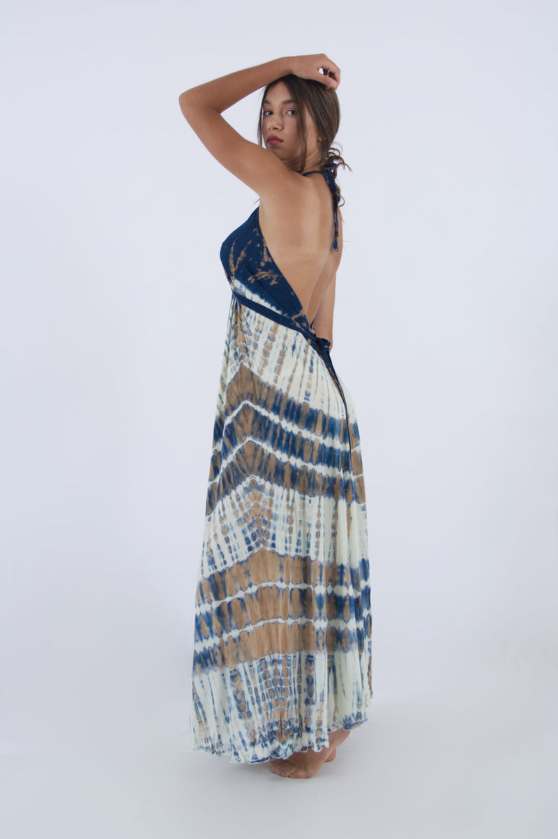 Model wearing a sexy holiday dress in blue and white tie dye, long with open back and halter neck.